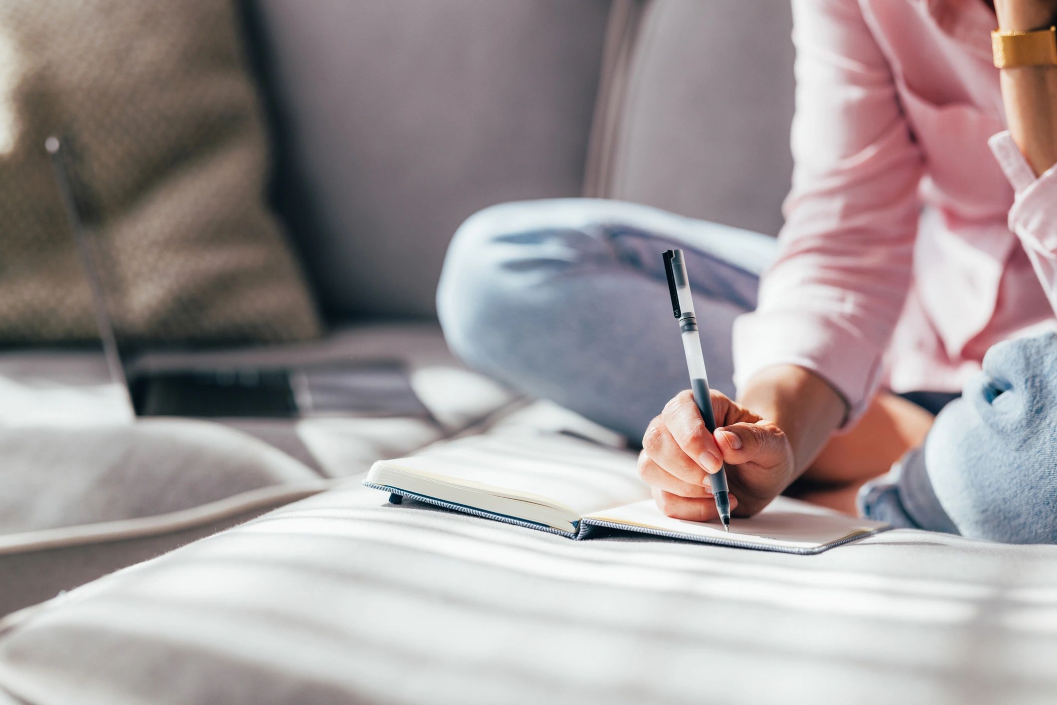 Person writing in a notebook in a calm, cozy setting